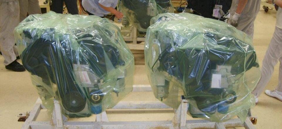Heavy-duty automobile motors wrapped in green GreenVCI shrink film on wooden pallets, protected with GreenVCI VCI powder packs for long-term corrosion prevention during storage and shipping.